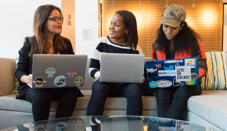 Three young women team-working on laptops